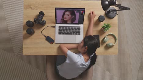 top view of asian woman editor sleeping while sitting in the workspace using a laptop next to the camera editing photo of a woman at home