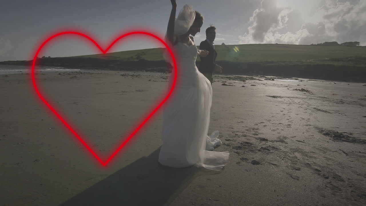 animación de corazón de neón sobre una pareja casada caucásica bailando en la playa