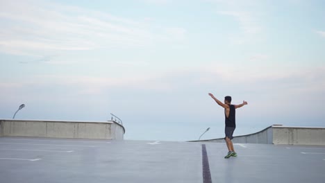 Man-runs-outdoors-on-the-parking-level-garage-with-outstretched-arms