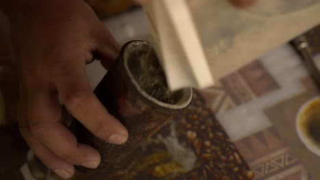 close-up man preparing tereré by loading refreshing yerba mate into the guampa, a natural refreshing drink from paraguayan tradition