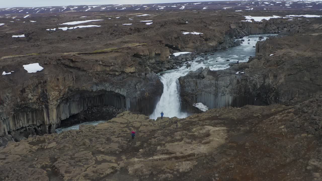 volando hacia las cascadas de aldeyjarfoss que fluyen en medio de la roca de columna de basalto en islandia