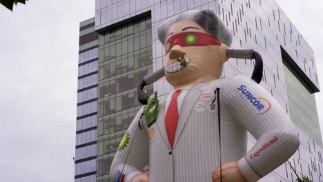 blow up evil capitalist ceo - queens park, toronto, canada - a huge human dummy displayed in the street nearby a commercial building - close up