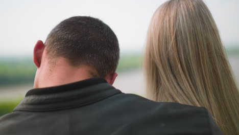 un tipo abraza a una mujer de pelo largo de pie frente a un pintoresco lago.