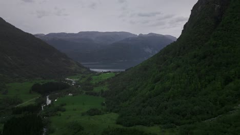 drone flies through a valley to a lake in norway surrounded by mountains