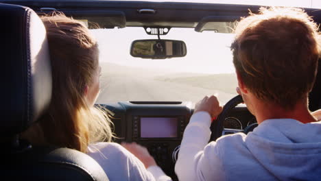 Young-couple-driving-with-sunroof-open,-rear-passenger-POV