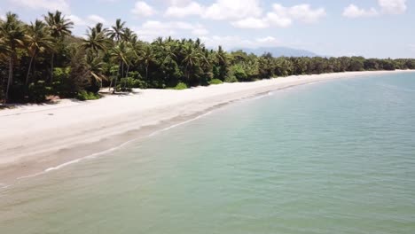 Drone-over-tropical-blue-waters-with-palm-trees-on-beach