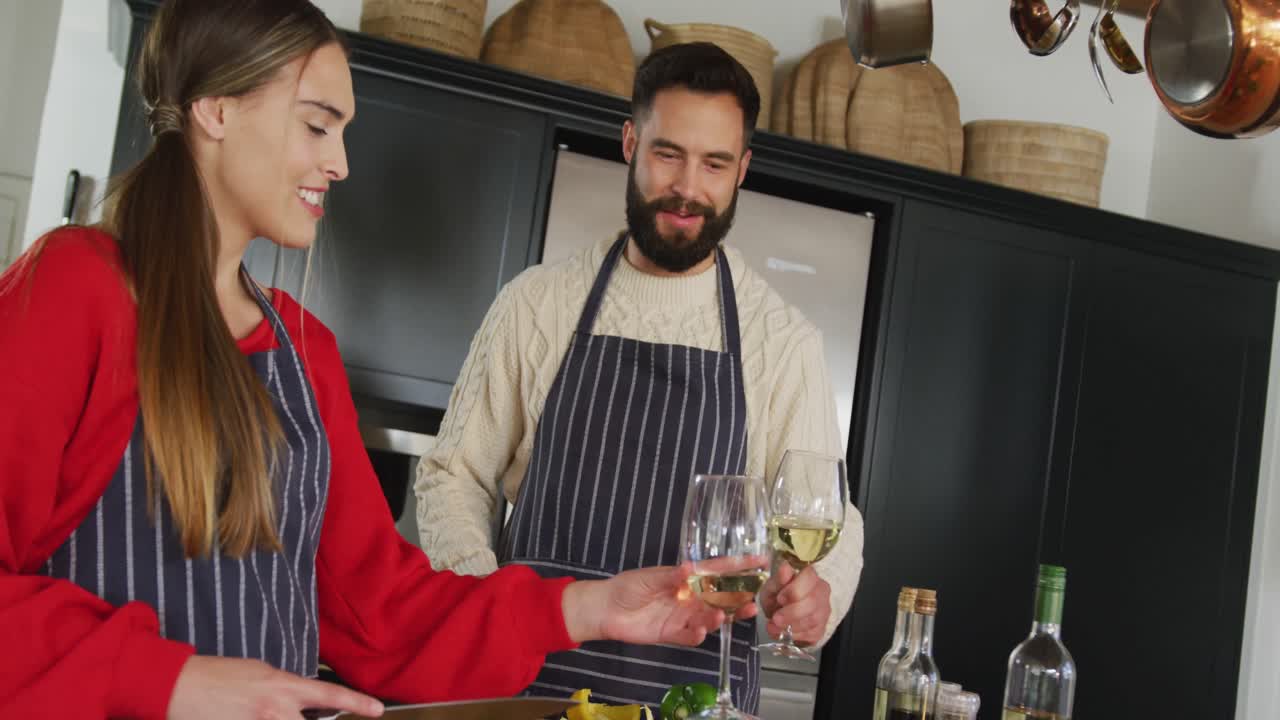 video de una feliz pareja caucásica cocinando y bebiendo vino