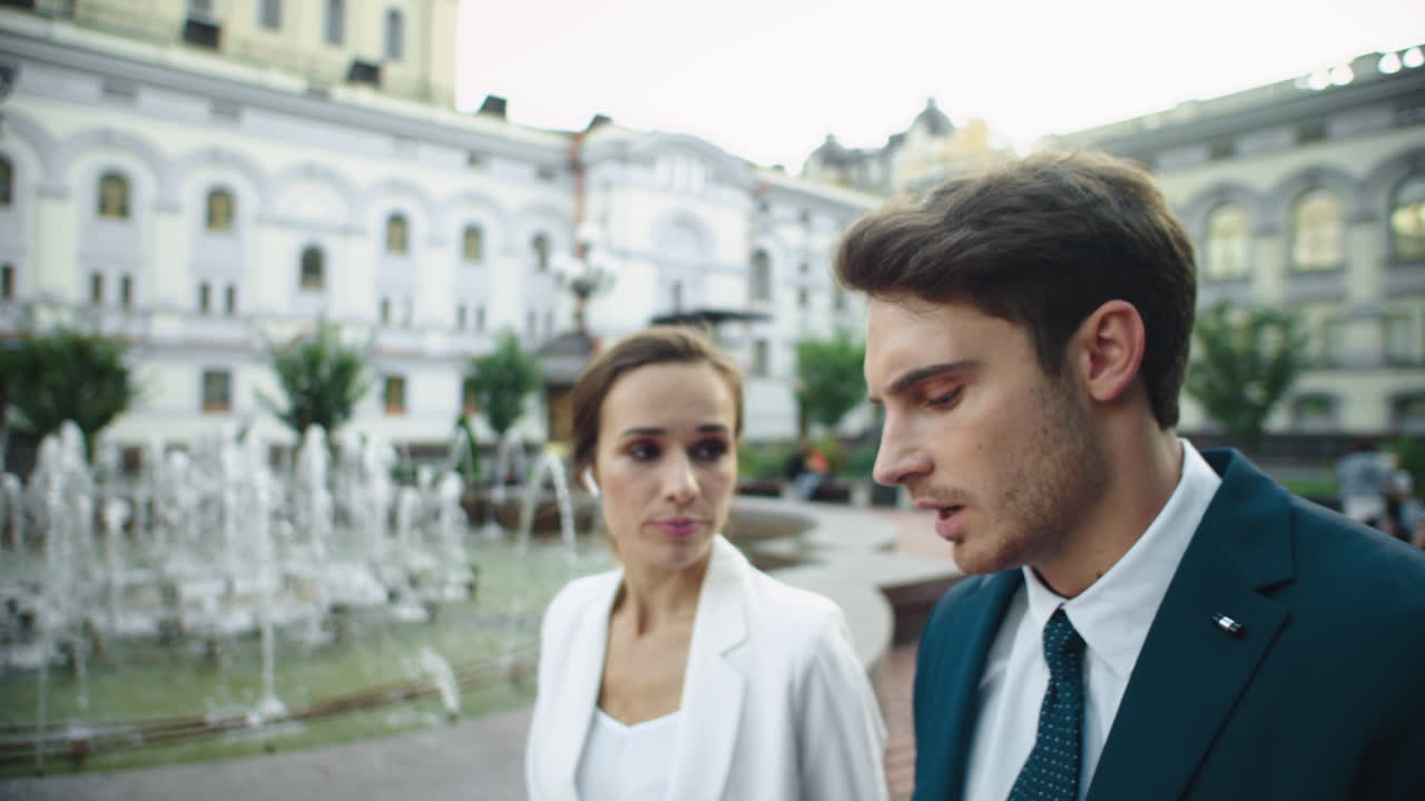 Uomo d'affari e donna d'affari infastiditi che discutono sui documenti durante una passeggiata in città
