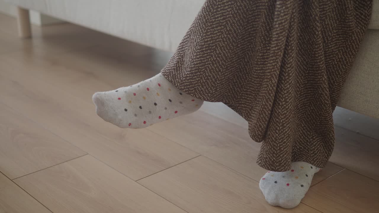 Feet in socks, wrapped in a brown blanket, on a sofa