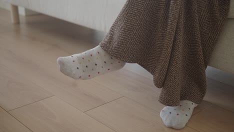 feet in socks, wrapped in a brown blanket, on a sofa