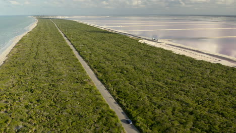 car driving on long coastline road between sea and salt ponds, mexico