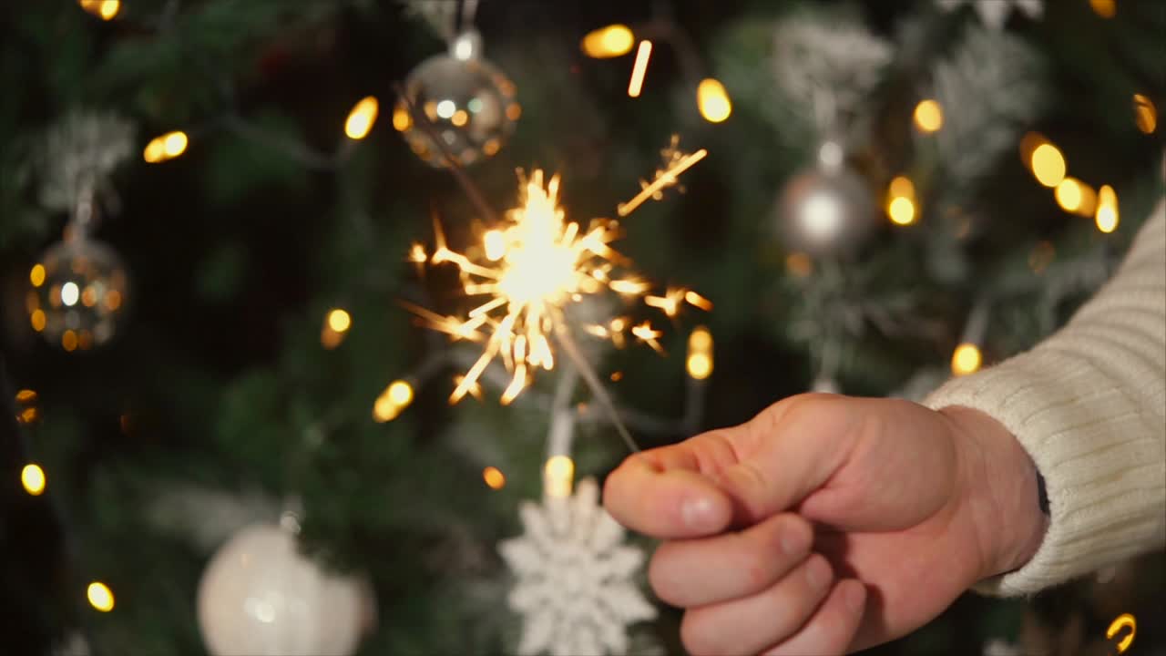 Sparkler in hand near Christmas tree