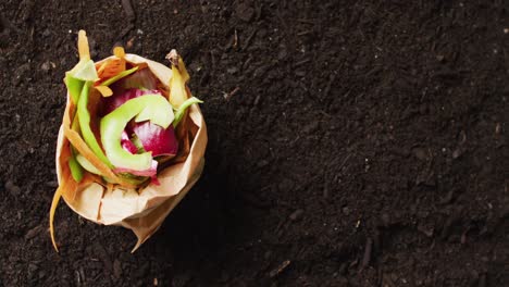 video of bag of organic fruit and vegetable waste for composting, on dark soil with copy space