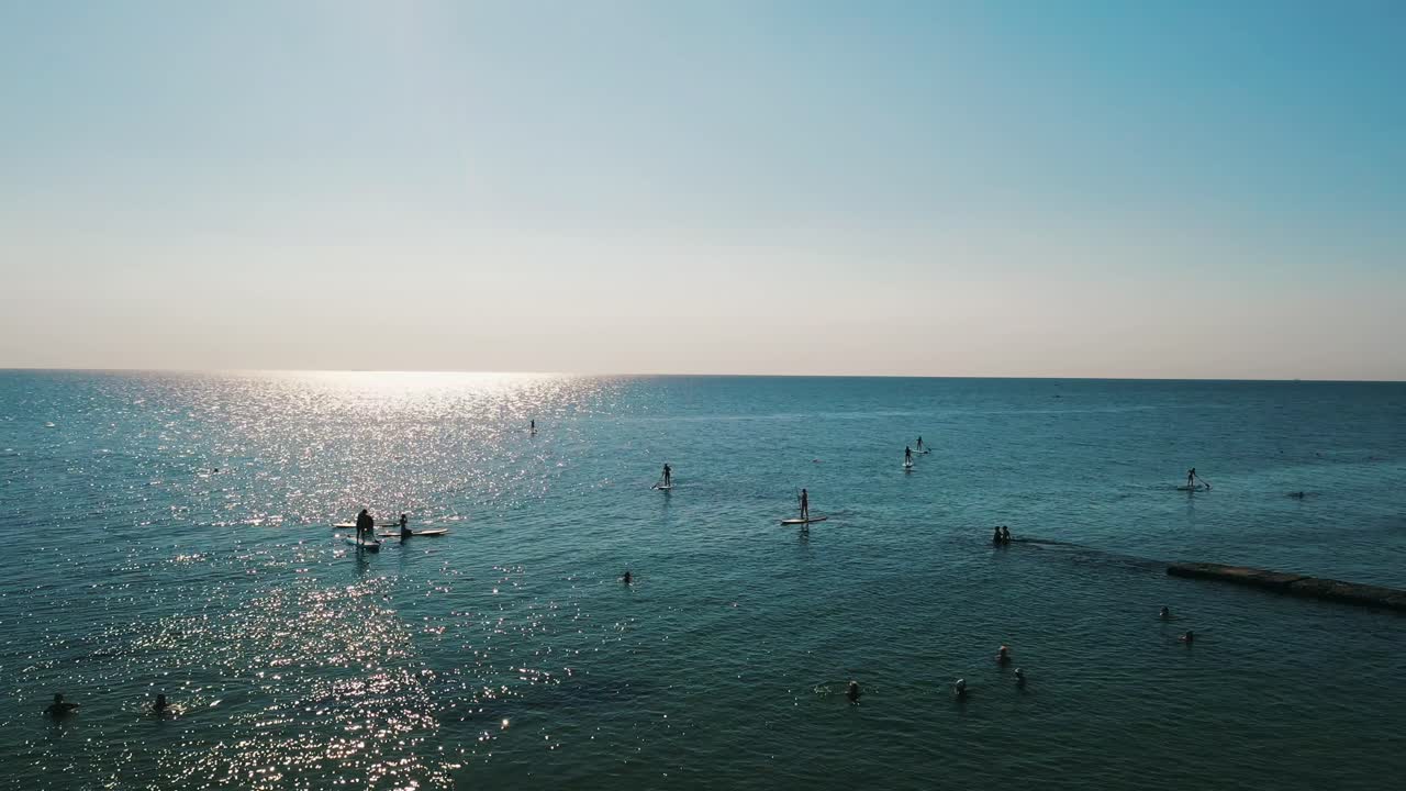 사람들이 해변에서 이 좋은 날에 패들보드에 서 있습니다.