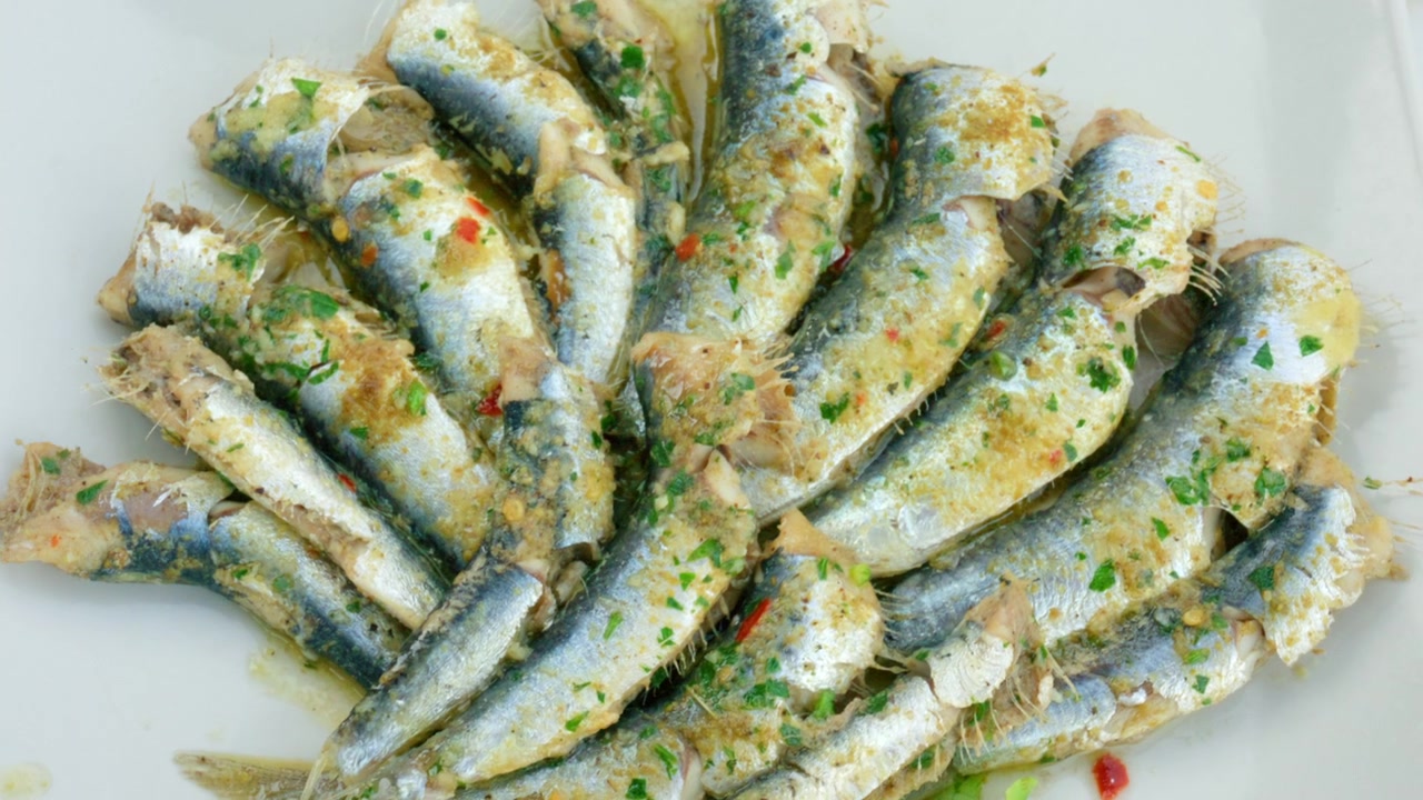 Muitas sardinhas cozidas numa marinada de ervas e azeite, um aperitivo típico de frutos do mar mediterrâneo, vista aproximada.