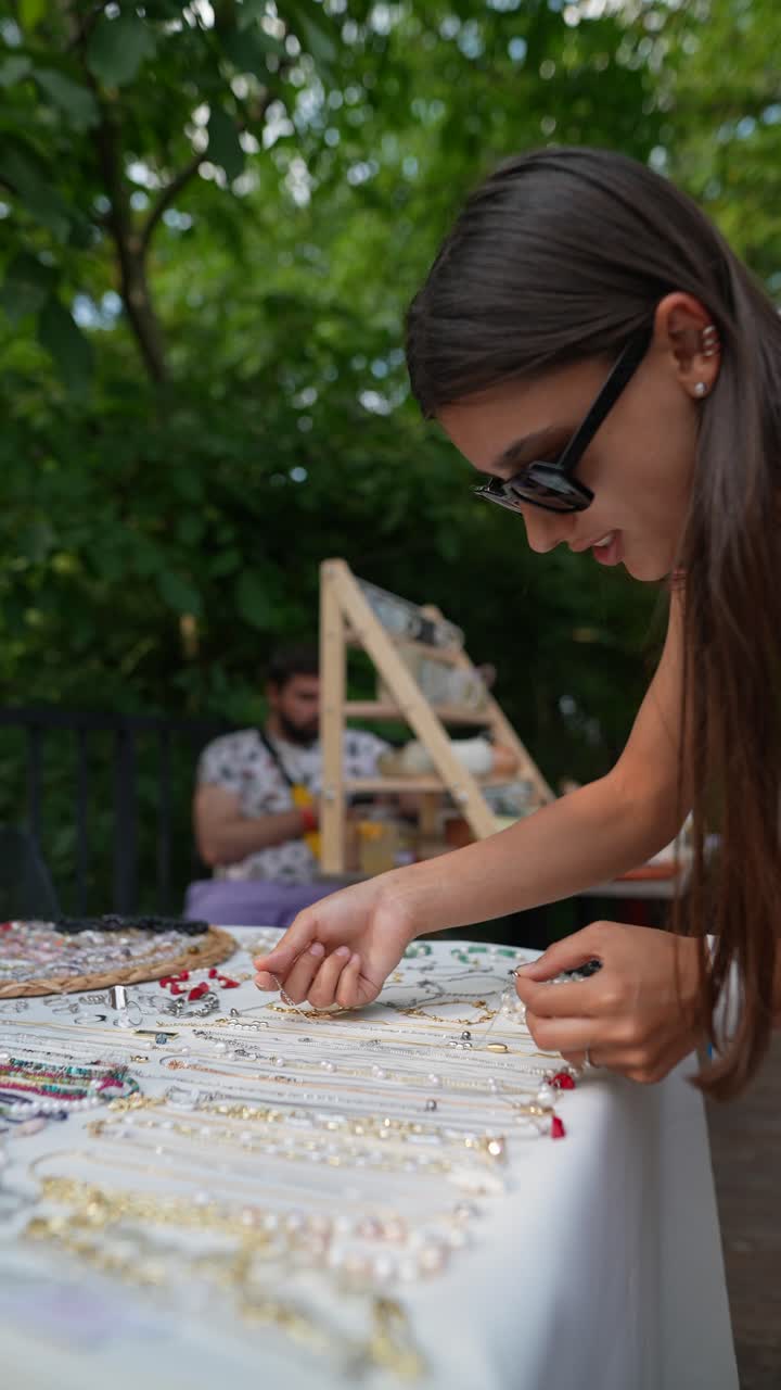 mujer mirando joyas hechas a mano en un mercado callejero