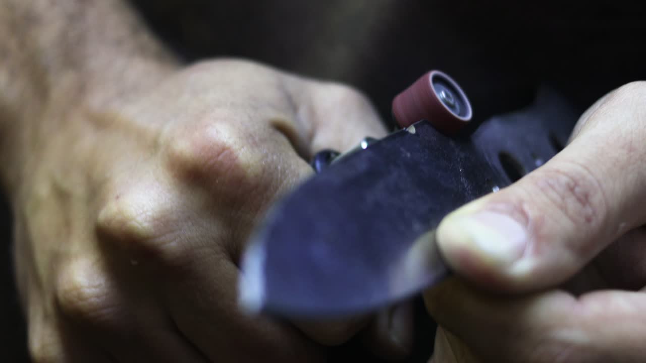 professional using dremel to sand knife and adjusting its format and shape