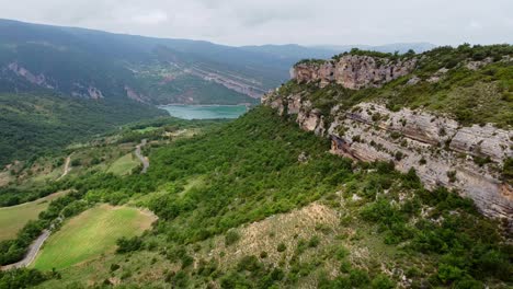 Cañón-Congost-De-Mont-Rebei-En-Ager,-Cataluña-Y-Aragón,-España---Vista-Aérea-De-Drones-De-Los-Escarpados-Acantilados-Rocosos,-El-Valle-Verde-Y-El-Lago-Azul-Esmeralda