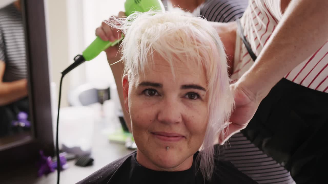 Vista frontale di una donna che si fa asciugare i capelli da un parrucchiere.