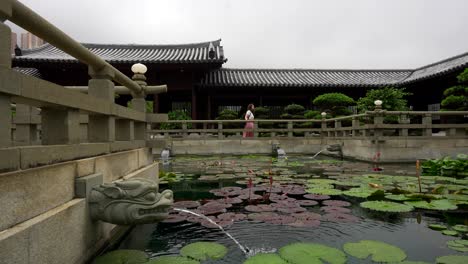 woman explores nan lian garden near a water lily pond with dragon-shaped pipes, hong kong, china