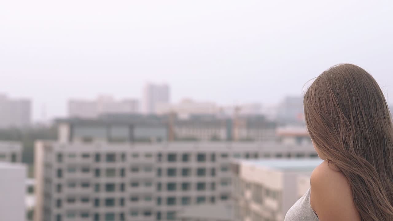 una chica de pelo largo se sienta y mira la ciudad turística en cámara lenta