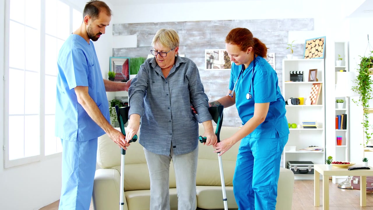Physical Therapists Assisting Senior Woman with Crutches in Living Room