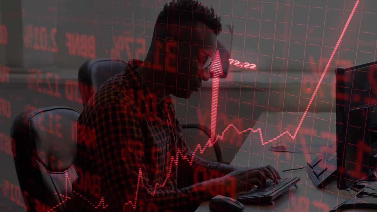 Mand taster på tastatur ved handelsbord, overlejret med røde aktiegrafer og numeriske værdier.