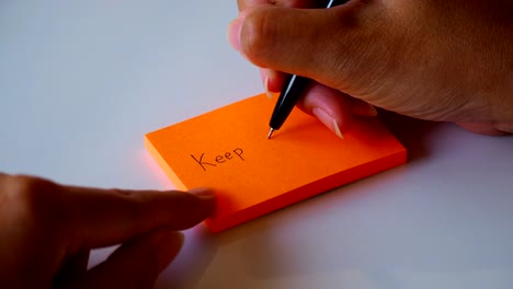 escribiendo a mano la palabra " seguir adelante " en naranja en un papel post it o una hoja de bloc de notas. imágenes de movimiento 4k