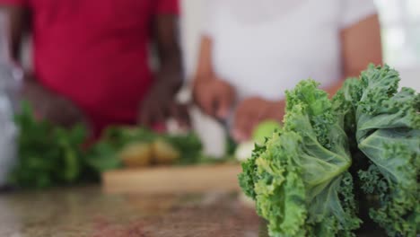 senior african american man and woman preparing fruit and vegetable health drinks at home