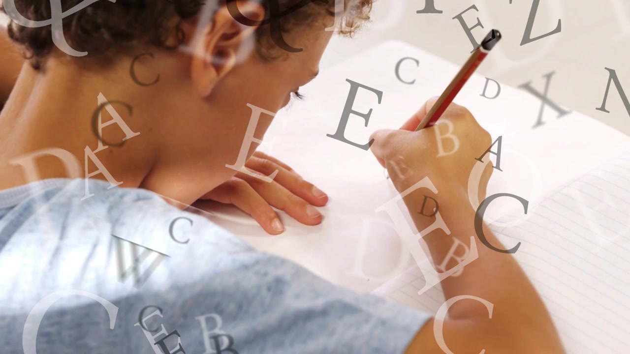 Boy leaning at table, pencil touching paper, learning letters with letters floating over hands