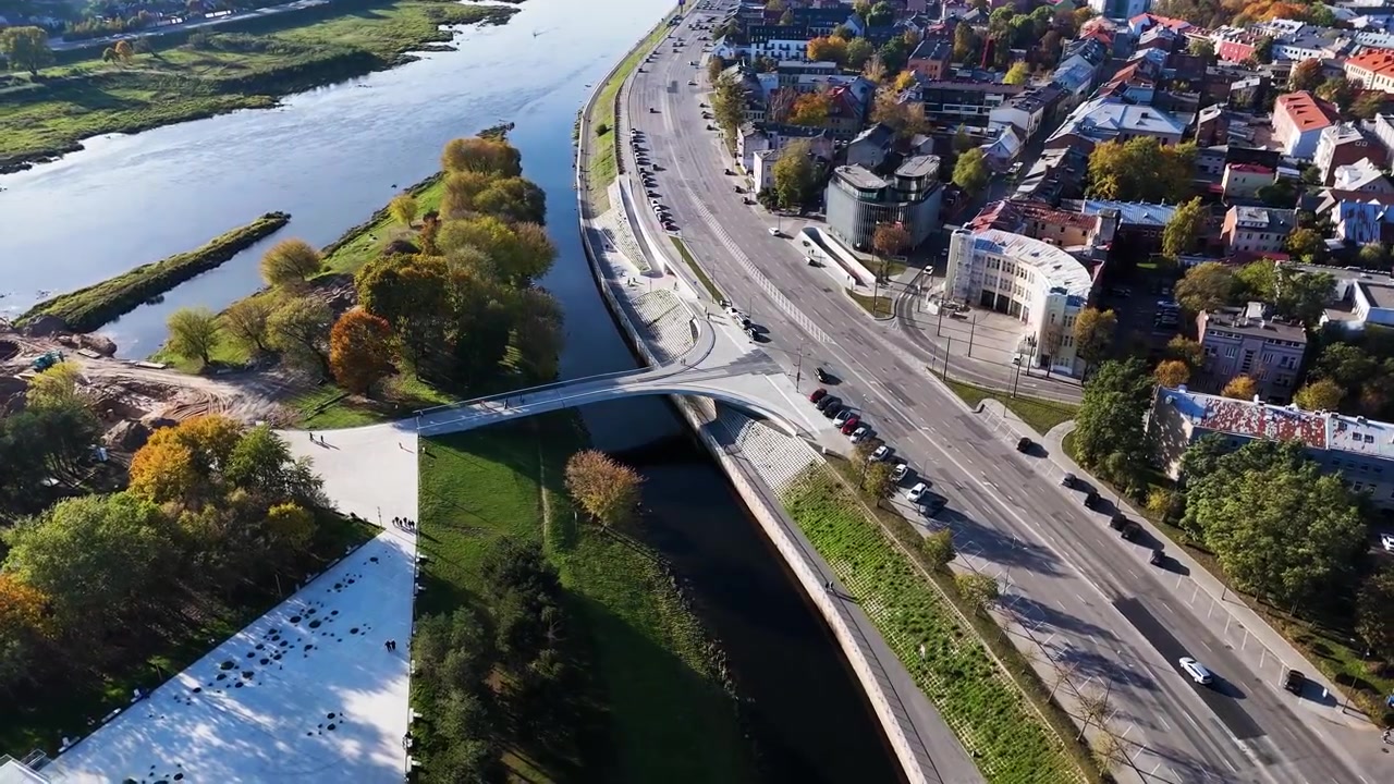 Vista aerea del centro di Kaunas, situato alla confluenza dei fiumi Neris e Nemunas, con un ponte pedonale e ciclabile di nuova costruzione, circondato dal fogliame autunnale, ripresa orbitante con drone.