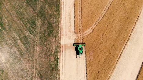 A-stunning-drone-perspective-capturing-a-combine-harvester-at-the-heart-of-lush-green-and-golden-crops,-showcasing-the-vibrant-diversity-of-the-agricultural-landscape