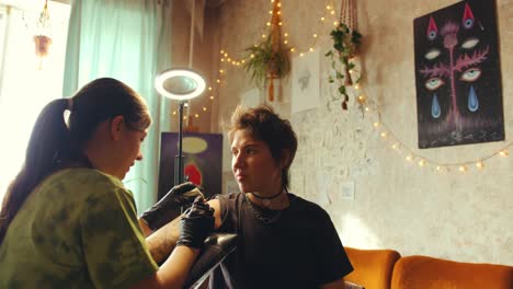 female tattoo artist working with client in home studio