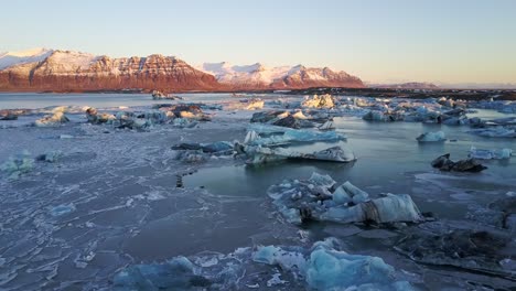 scenic views across a lake of icebergs during morning sunrise in iceland