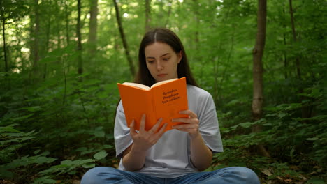 young woman reading a book in the forest