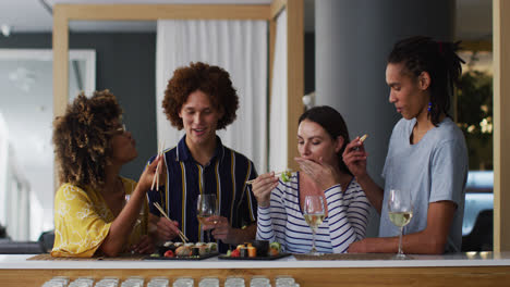 Diverse-group-of-happy-friends-drinking-wine-eating-sushi-and-talking-at-a-bar