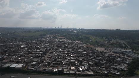 Push-in-drone-shot-glides-over-the-township-of-Alexandra-in-Johannesburg,-offering-a-glimpse-of-the-energetic-cityscape-and-rapid-transportation-in-motion