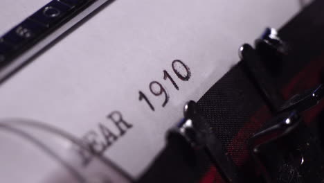 year 1910, typing on white paper in vintage typewriter, macro close up