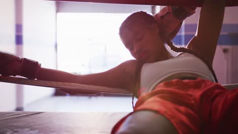 mujer de raza mixta descansando en el gimnasio de boxeo