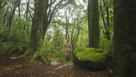 woman enjoying lush green outdoor forest in new zealand, rob roy hike track