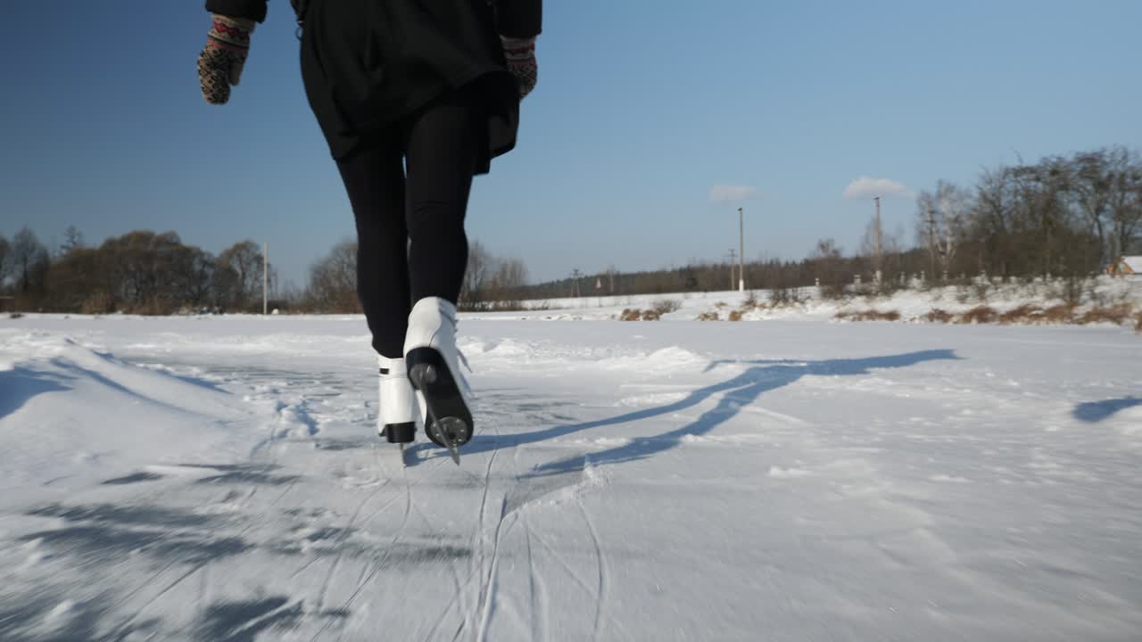 Winterschlittschuhlaufen auf dem See. Weibliche Füße in weißen Eiskunstlaufschuhen auf dem Eis. Frau läuft im Winter auf zugefrorenem Teich Schlittschuh. Winteraktivitäten