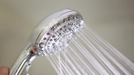 la mano masculina gira un interruptor en el cabezal de la ducha para cambiar entre las diferentes configuraciones de chorro