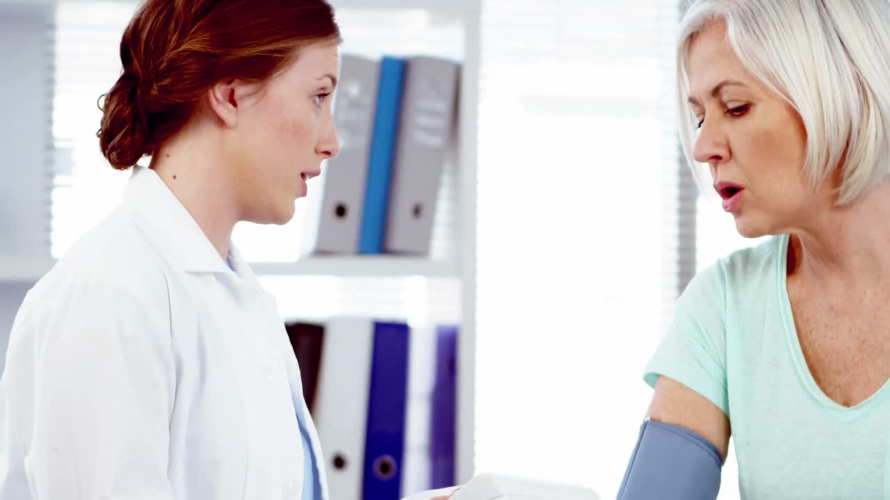 Medico femminile che controlla pressione sanguigna del paziente