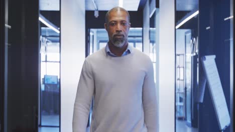 Businessman-walking-and-looking-at-camera-in-modern-office