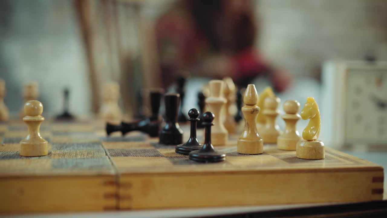 Close up of gloved hand pushing black pawn during chess game on wooden board with blurred background, symbolizing strategy, survival, decision making, and focus