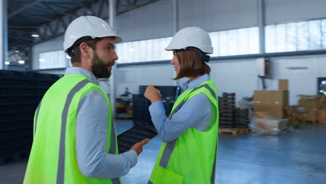 especialistas de almacén comprobando la producción de la fábrica sosteniendo tabletas de papel hablando