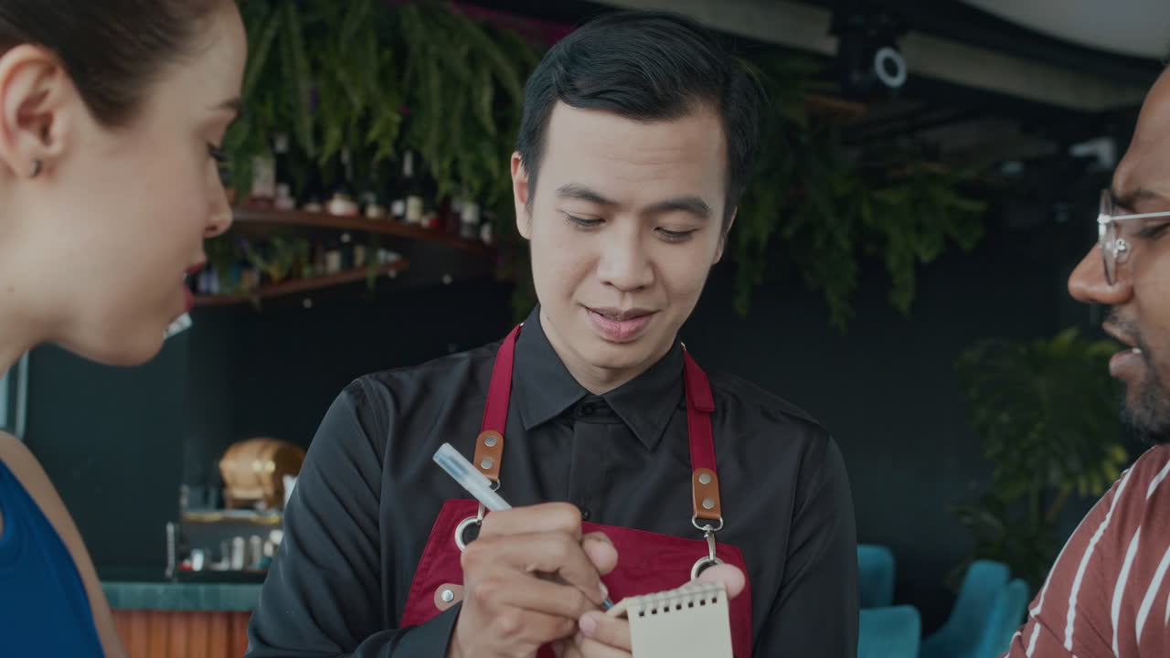 Waiter Listening to Guests Ordering Dinner at Restaurant