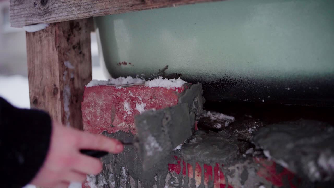 그 남자는 시멘트를 사용하여 diy 핫   아래의 벽돌을 고정하고 있습니다.