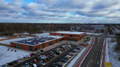 Indoor swimming pool with solar panels surrounded by snow and suburban homes in Falkensee Germany. Nice aerial view flight static tripod hovering drone