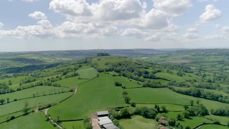 sideways aerial of a solitary hill in a vast countryside landscape in late spring